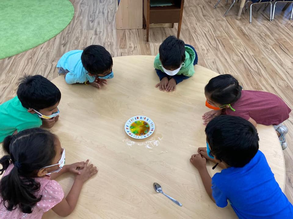 kids knelt over a table all facing each other